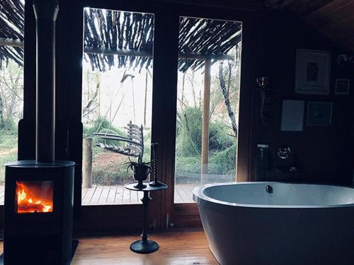 a bathroom with a bath tub and a fireplace at De Cango Farm in Oudtshoorn