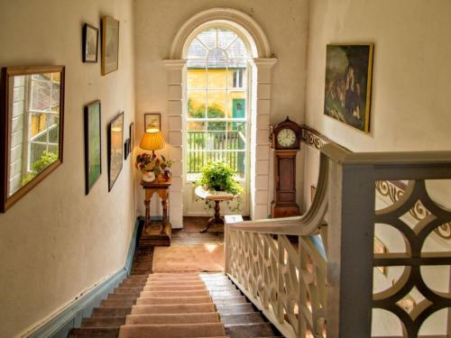 uma escada numa casa com uma janela e um relógio em Roundwood House em Mountrath