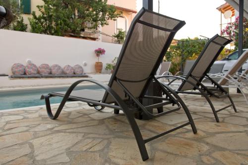 two lawn chairs sitting next to a pool at Nicola's Apartments in Kassiopi