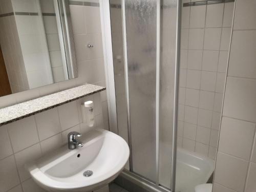 a white bathroom with a sink and a shower at Rügen-Hotel in Sassnitz