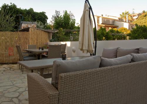 a patio with a couch and a table and an umbrella at Nicola's Apartments in Kassiopi