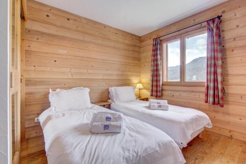 Ce lit se trouve dans un dortoir doté de murs en bois et d'une fenêtre. dans l'établissement Rose et Chardon - Snow and Trek, à Morzine