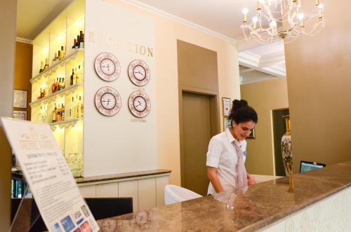 a woman standing at a counter in a store with clocks at Parish Hotel in Svilengrad