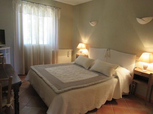 una camera da letto con un letto con due lampade e una finestra di CHAMBRE D'HÔTE LE GRAND BARSAN a Vaison-la-Romaine