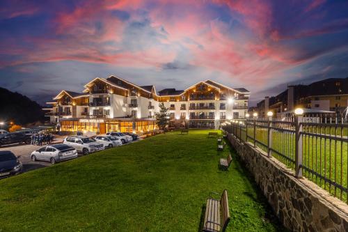 un grande edificio con auto parcheggiate in un parcheggio di Crystal Hotel & SPA a Bakuriani