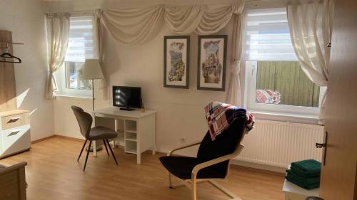 a living room with a desk with a computer and two chairs at Pension zur 23 in Kurort Altenberg