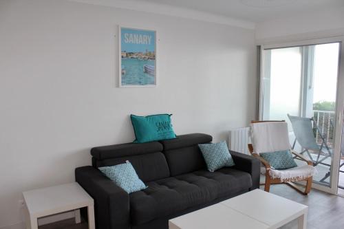 - un salon avec un canapé noir et une chaise dans l'établissement Les Baux 1, à Sanary-sur-Mer