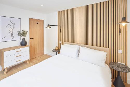 Un dormitorio con una cama blanca y una pared de madera. en Host & Stay - Golden Lion Apartments, en Whitby