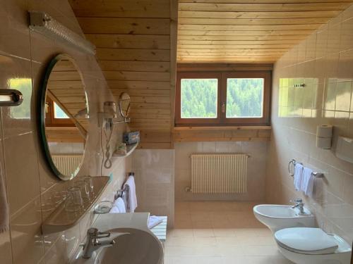 オルティゼーイにあるHotel Fortunaの洗面台、トイレ、鏡のあるバスルーム