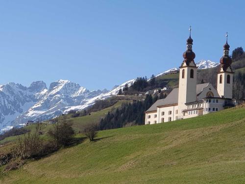 a church on a hill with mountains in the background at Haus Anna Ein Haus mit Herz in Fliess