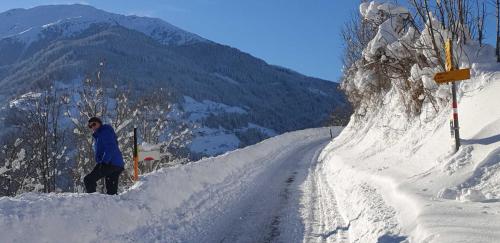 a man standing on the side of a snow covered road at Haus Anna Ein Haus mit Herz in Fliess