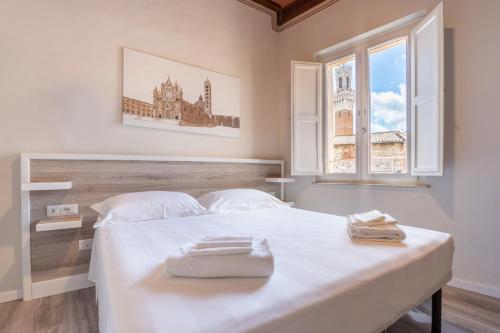 um quarto com uma grande cama branca e uma janela em Albergo Centrale em Siena