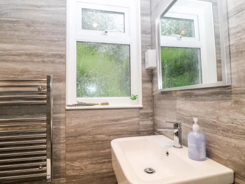 a bathroom with a sink and two windows at Lavender Lodge in Callington