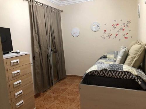 1 dormitorio con 1 cama, vestidor y TV en LAS CANTERAS, en Las Palmas de Gran Canaria