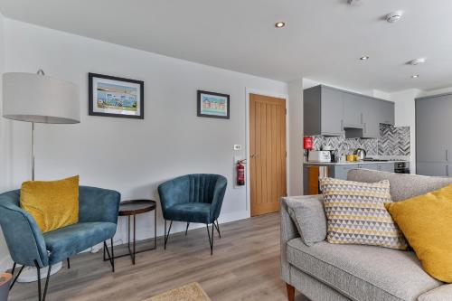 a living room with a couch and chairs and a kitchen at Finest Retreats - 13 Belle House - Apartment 1 in Filey