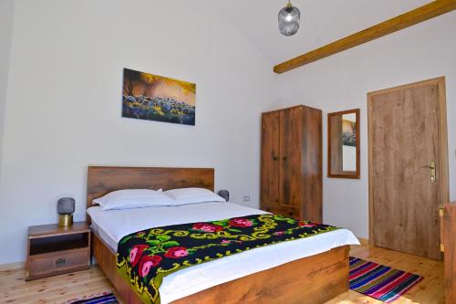 1 dormitorio con 1 cama grande con una manta colorida en Pensiunea Huda lui Papară en Sub Piatra