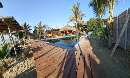 a swimming pool with a wooden deck next to the beach at Mamaqocha in Canoas De Punta Sal