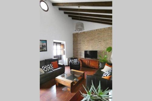 a living room with black furniture and a brick wall at Casa Cerros de Úbeda 1630 in Úbeda
