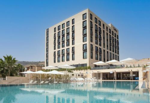 a hotel with a large swimming pool in front of a building at Sofia Hotel Sea Of Galilee in Tiberias