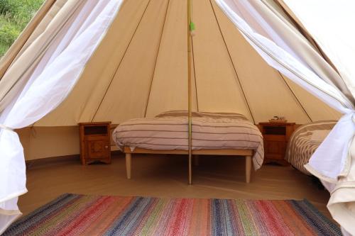 een tent met 2 bedden en een tapijt in een kamer bij Glamping la Cascina d'Orleans in Saint-Pierre