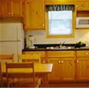 a kitchen with a table and a sink and a window at Cabot Trail Sea & Golf Chalets in Chéticamp