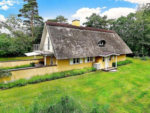 a yellow house with a thatched roof on a yard at 8 person holiday home in Vig in Vig