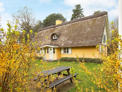 a yellow house with a thatched roof and a picnic table at 8 person holiday home in Vig in Vig