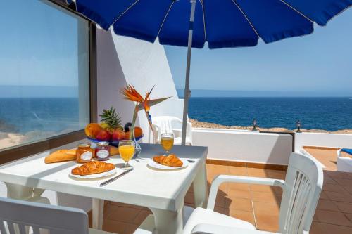 a white table with food and drinks and an umbrella at Reyes Natur in Charco del Palo
