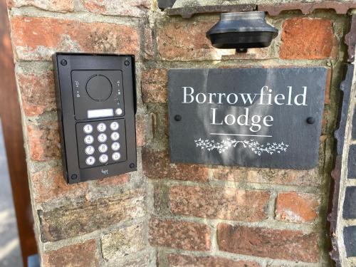 een bord op een stenen muur met een geautoriseerde lodge bij Borrowfield Lodge in Derby