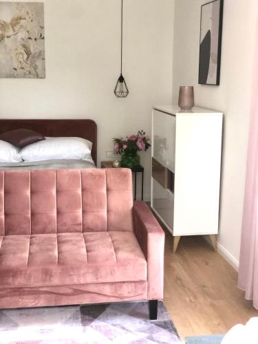 a living room with a pink couch and a bed at Duna P'Art Panzió in Verőce