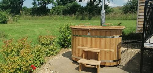a wooden gazebo with two benches in a yard at Fair Farm Hideaway in Waltham on the Wolds