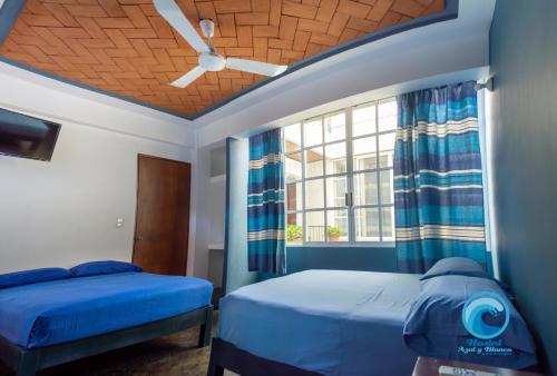 a bedroom with two beds and a window at Hostal Azul y Blanco in Santa Cruz Huatulco