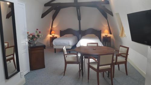 a room with a table and a bed and a tv at La Source du Mont in Saint-Martin-Valmeroux