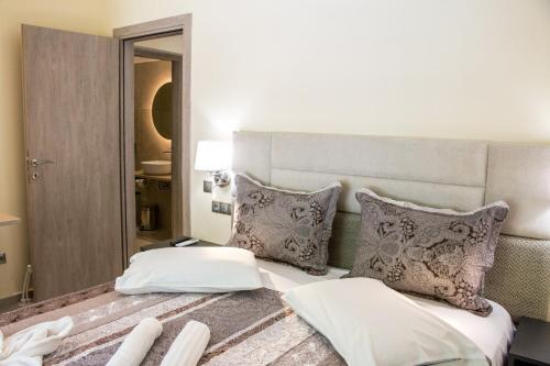 a bedroom with a large white bed with pillows at Glyfada Beach Hotel in Glyfada