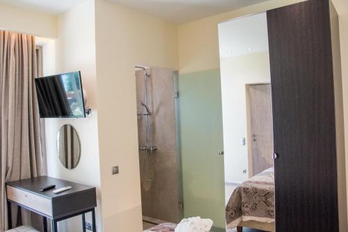 a bathroom with a shower and a sink and a mirror at Glyfada Beach Hotel in Glyfada