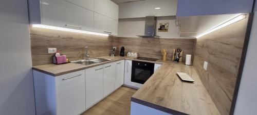 a kitchen with white cabinets and a wooden counter top at Svir Skyline Apartment No 39 in Ohrid