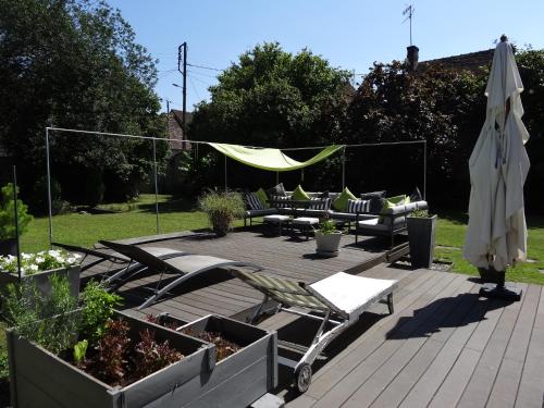 une terrasse en bois avec des chaises, un parasol et des chaises dans l'établissement Les Petites Tuileries, à Bray-sur-Seine