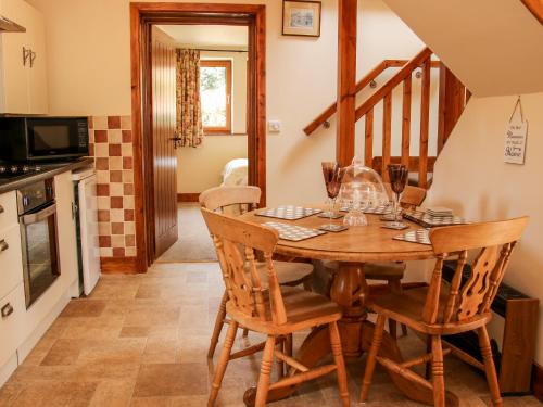 a kitchen and dining room with a wooden table and chairs at Pool Barn in Craven Arms