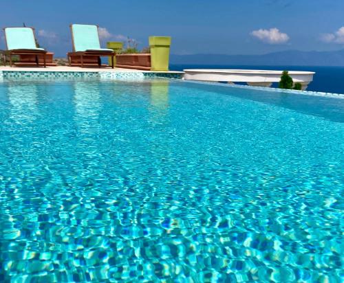 a swimming pool with blue water and two chairs at Villa Ulyana Kriaritsi - Athos Sea View & Spa in Kriaritsi