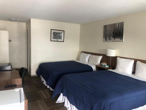 a hotel room with two beds with blue sheets at Houston Motor Inn in Houston