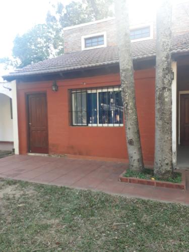 a house with an orange garage with a tree at Hermosa Casita II Paso Patria in Paso de la Patria