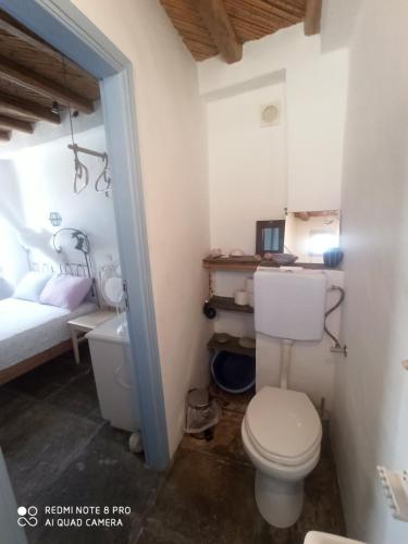 a bathroom with a toilet and a bed in a room at Traditional stone house with breathtaking view in Serifos Chora