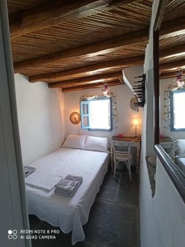 a small bedroom with a bed and a table at Traditional stone house with breathtaking view in Serifos Chora