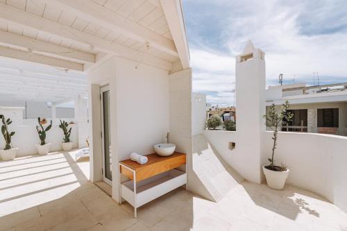 a balcony with white walls and a wooden table at Infinito Bianco in Polignano a Mare