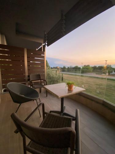 d'une terrasse avec une table, des chaises et une fenêtre. dans l'établissement Levanda suites, à Paralia Katerinis