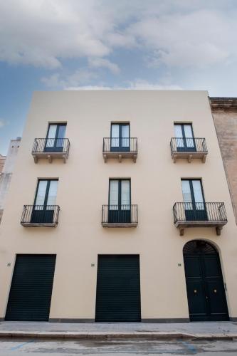 a white building with black doors and balconies at 32Venti Comfort Apartments Trapani in Trapani
