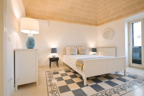 a white bedroom with a bed and a window at Pietro Maggi - Apulian Historical House in Manduria