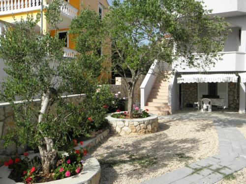 einen Innenhof vor einem Gebäude mit Bäumen und Blumen in der Unterkunft Apartments Babić in Novalja