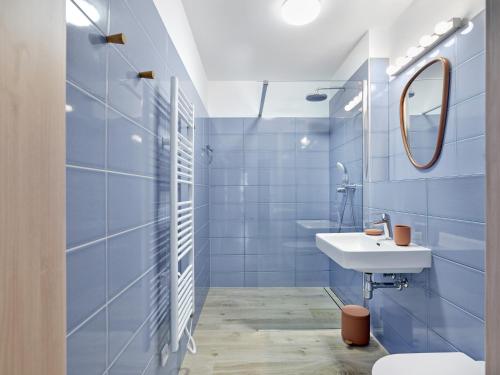 La salle de bains bleue est pourvue d'un lavabo et d'un miroir. dans l'établissement Apartmány Velká Morava, à Dolní Morava