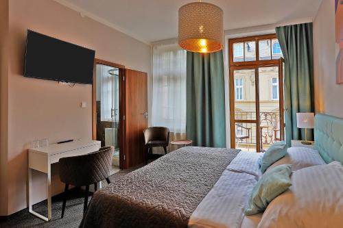 a hotel room with a bed and a desk and a television at Hotel Pilgrim in Karlovy Vary